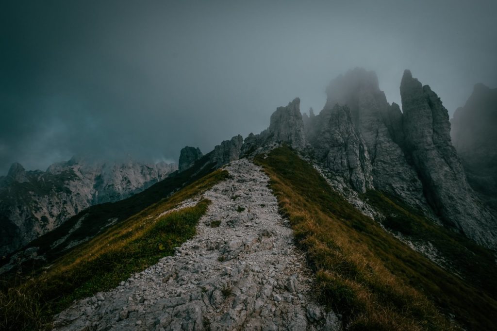 green grass field and mountain under gray clouds