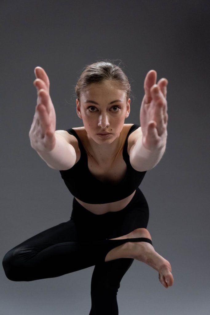 woman in black tank top and black leggings doing yoga