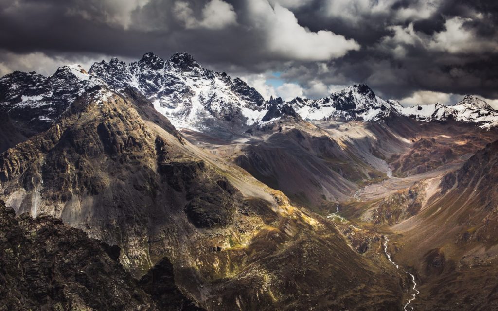 brown and white mountains under white clouds